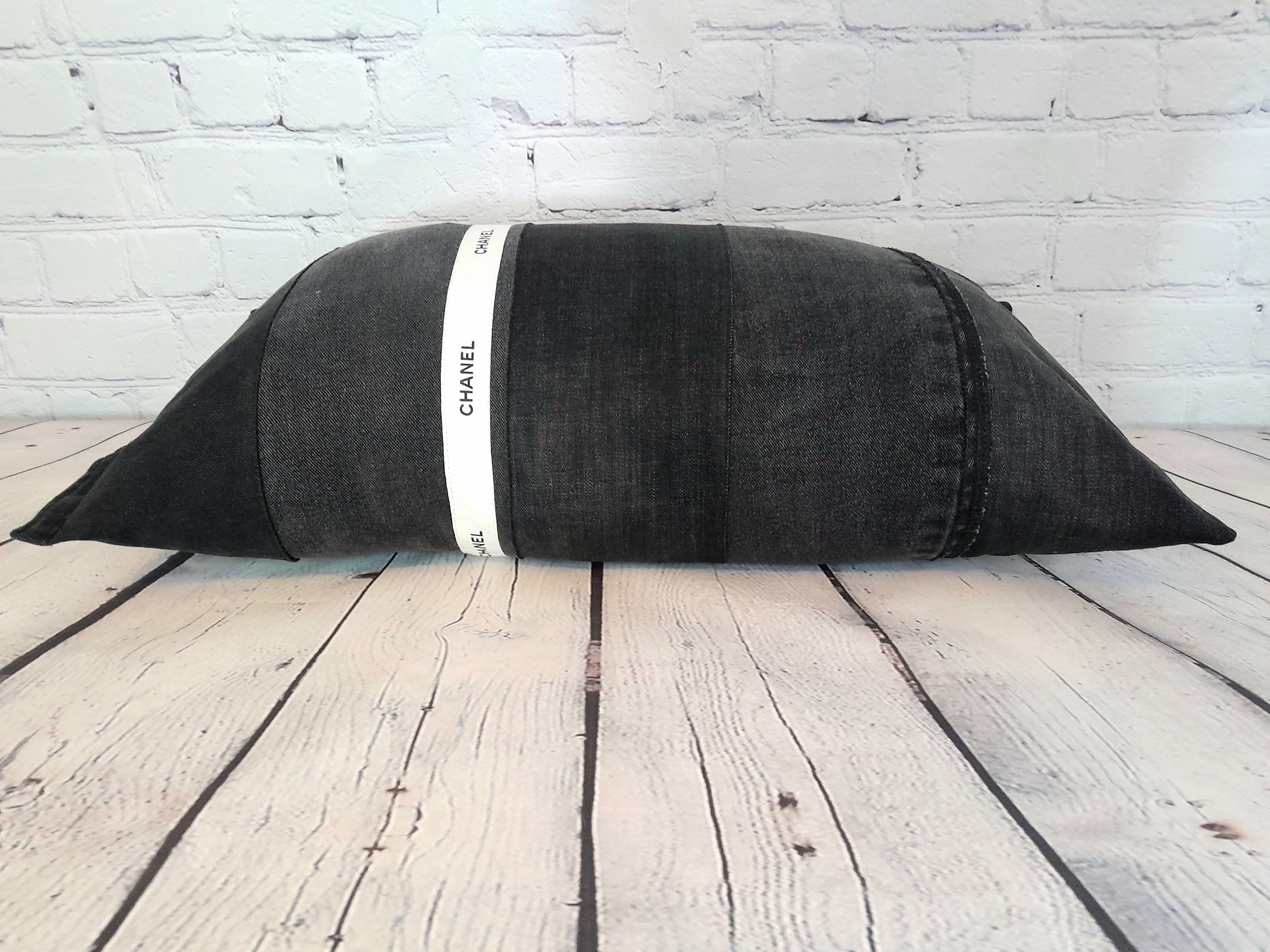 Patchwork bolster cushion pillow made by upcycling waste black denim and white Chanel ribbon.